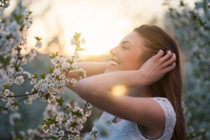 Glück Symbolbild - Frau freut sich an Frühlingsblumen