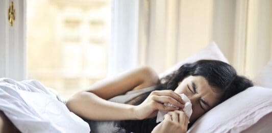 erkältete frau im bett liegend