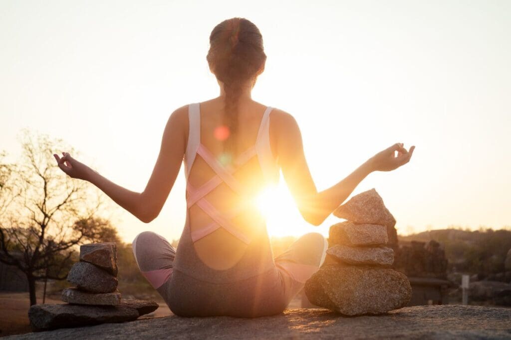 Frau in Meditationshaltung der Sonne zugewandt