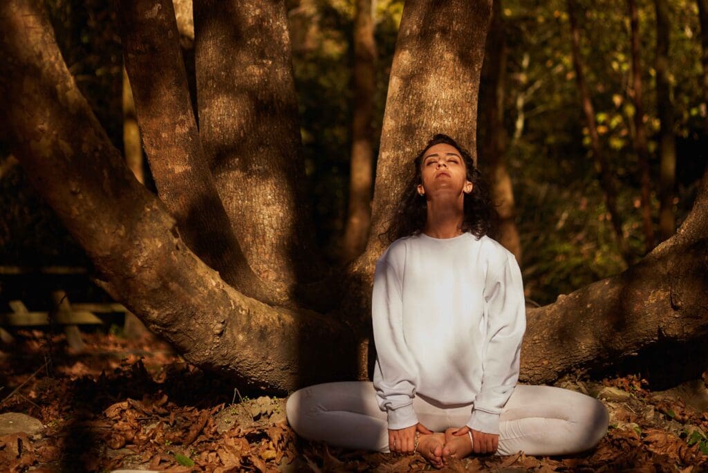 Yoga, Herbst, eine Frau sitzt an einem Baum mit geschlossenen Augen, Fotocredit: millionsjoker von Getty Images Signature