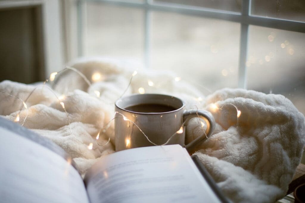 Buch mit Tasse Kaffee und Kuscheldecke