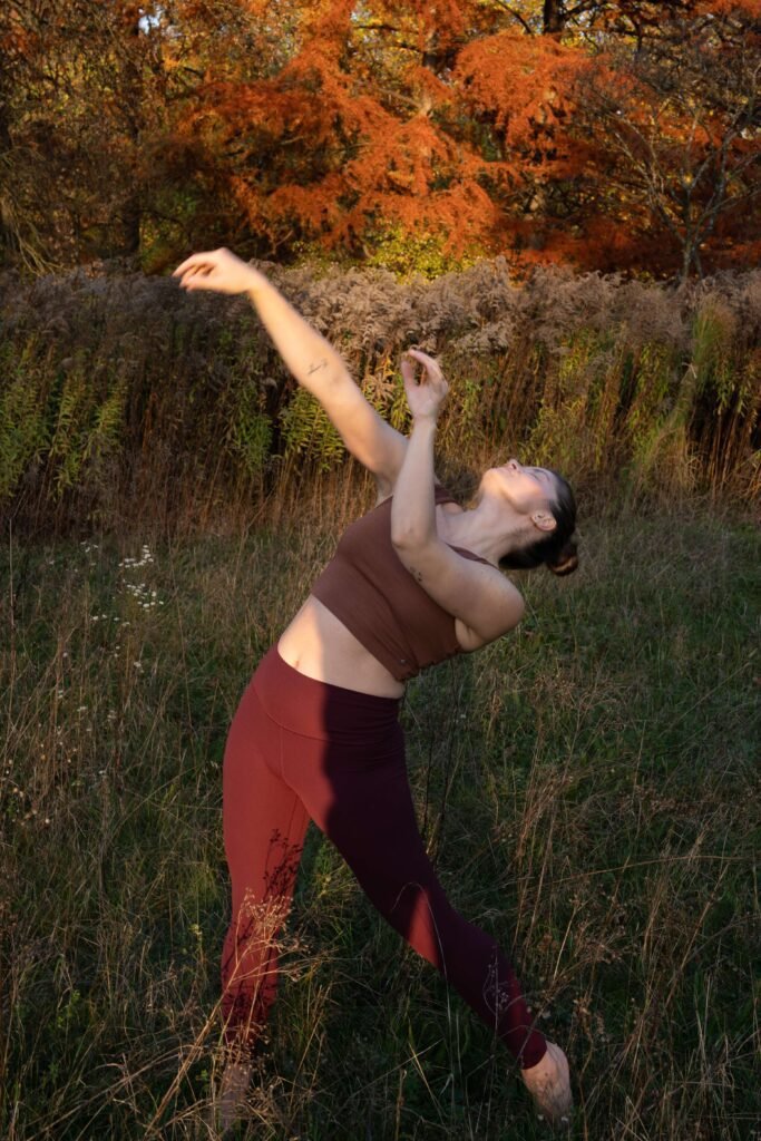 Daniela Mühlbauer, eine Frau tanzt draußen im im hohen Gras, Chakra Journey, Yoga