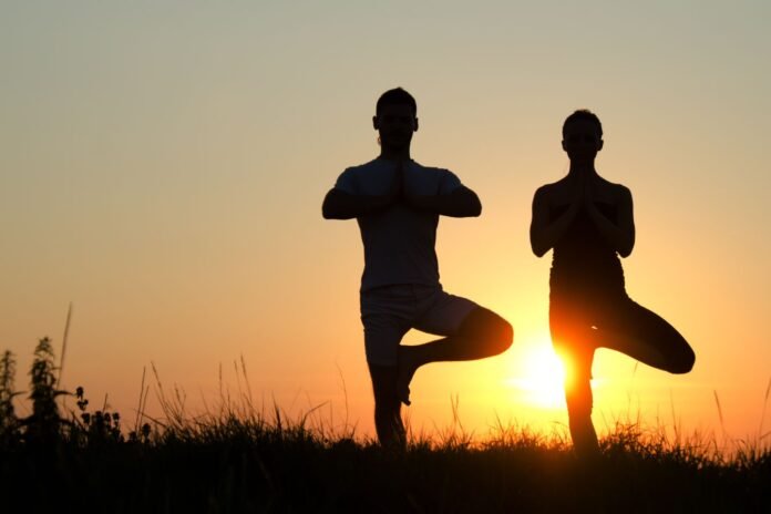 Pärchen macht Yoga vor Sonnenuntergang